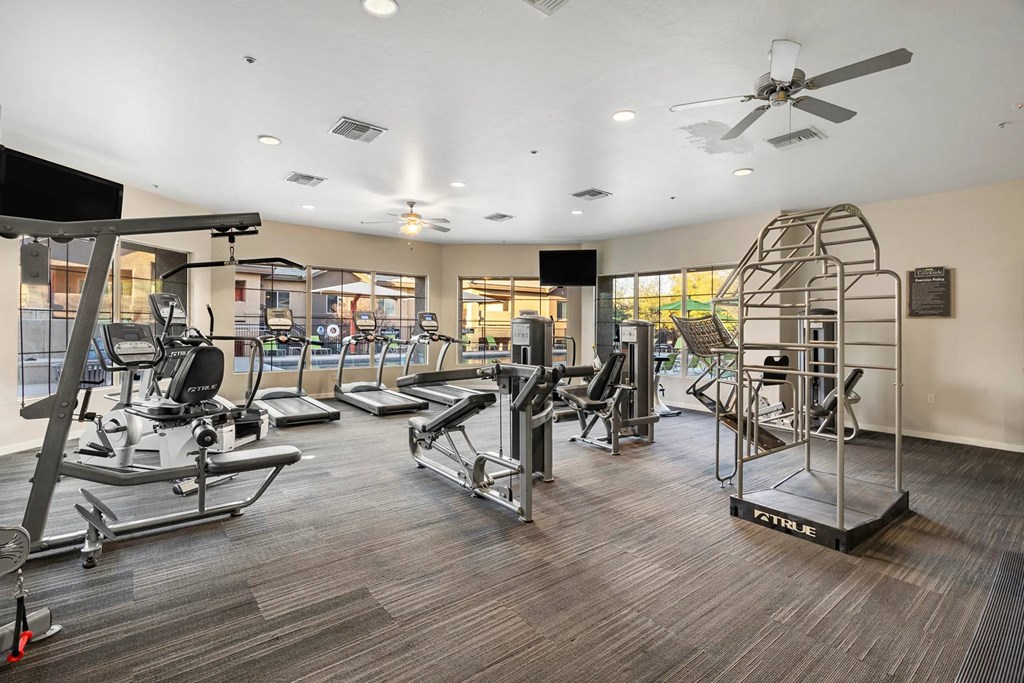 A gym with a variety of equipment including treadmills, weights, and a stair climber.