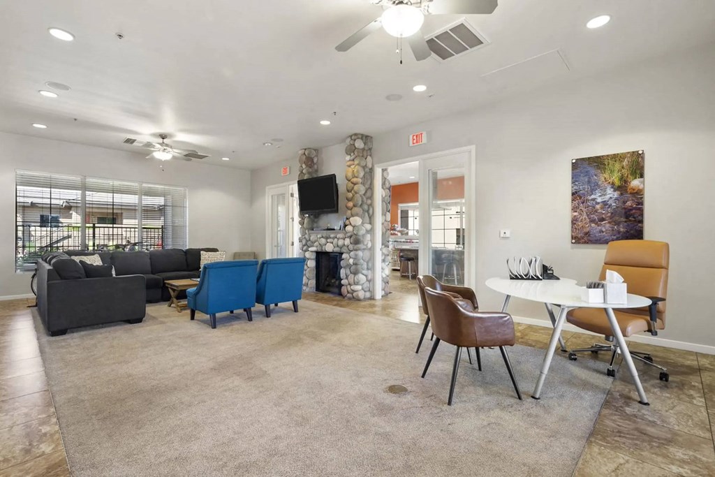 A living room with a black couch, blue chairs, and a television.
