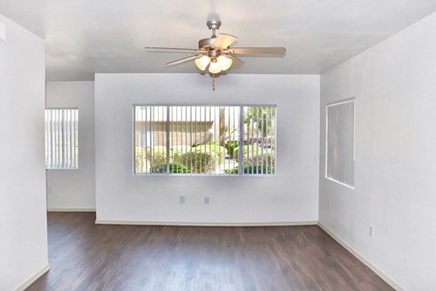 A room with a ceiling fan and a window with blinds.