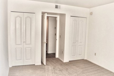 A room with three doors and a carpeted floor.
