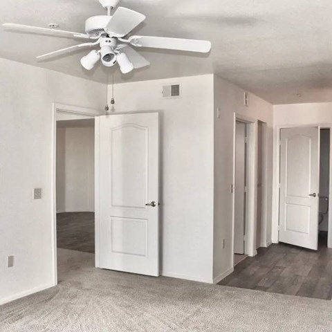 A white room with a ceiling fan and a carpeted floor.