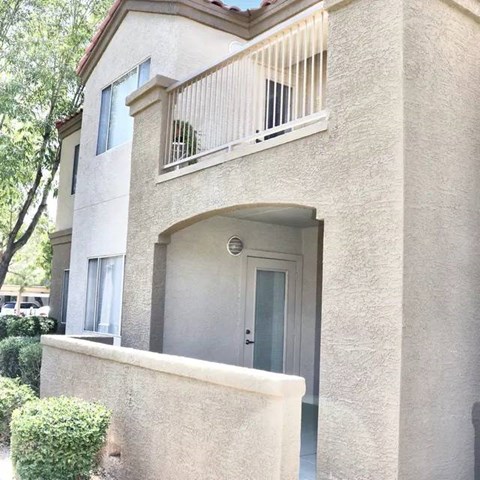 A beige house with a balcony and a door.