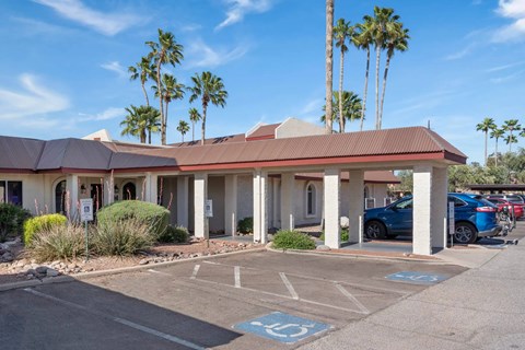 A parking lot with a building and palm trees in the background.