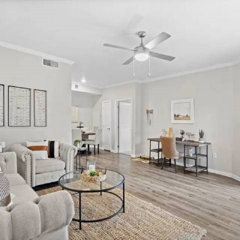 A living room with a grey couch, a coffee table, and a dining table with chairs.