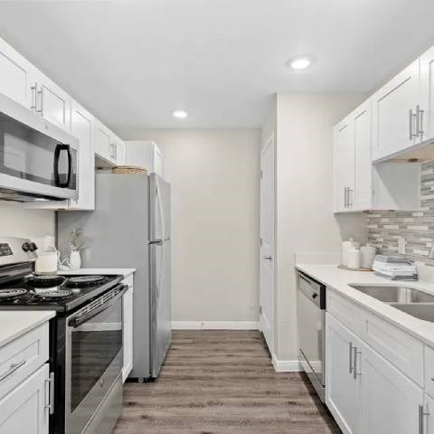 A kitchen with white cabinets and appliances.
