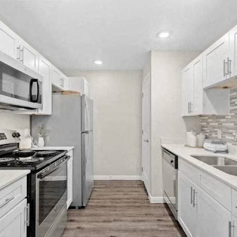 A kitchen with white cabinets and appliances.
