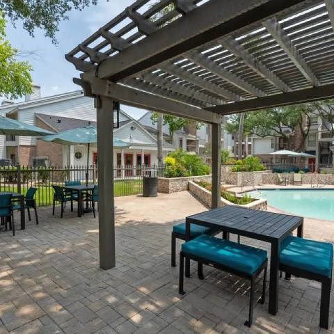 A patio with a table and chairs under a pergola.