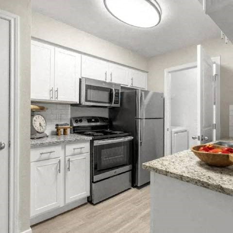 A kitchen with white cabinets and a granite countertop.