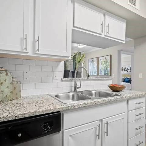 A kitchen with white cabinets and a granite countertop.