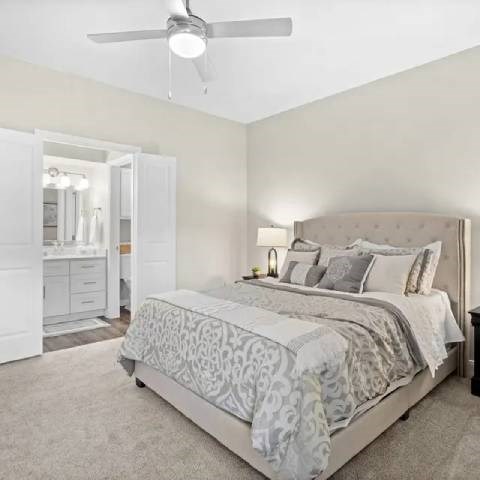 A bedroom with a large bed and a ceiling fan.