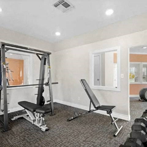 A home gym with a bench, weights, and a barbell.