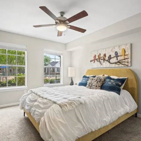 A bedroom with a large bed and a ceiling fan.