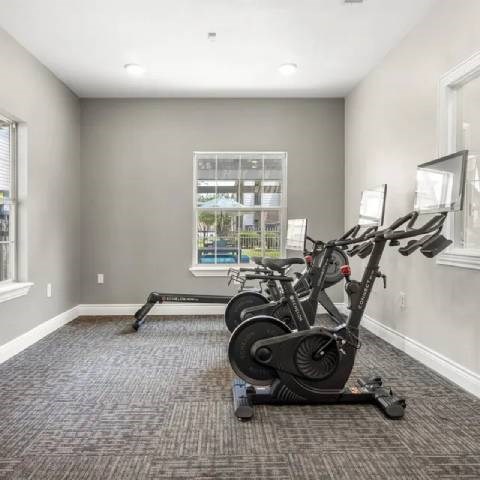 A room with a grey carpet and a window showing a view of a building and trees outside.