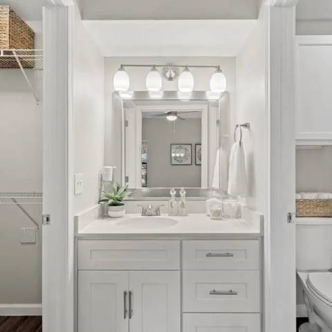 A white bathroom with a mirror, sink, and towel rack.