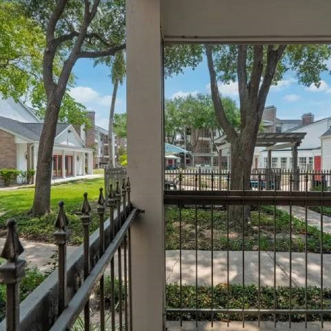 A view from a balcony looking out at a tree and a building.