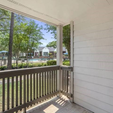 A balcony with a view of a pool and trees.