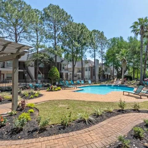 A pool surrounded by a grassy area and trees.