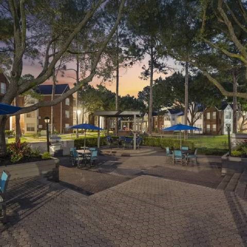 A sunset view of a courtyard with tables and chairs.