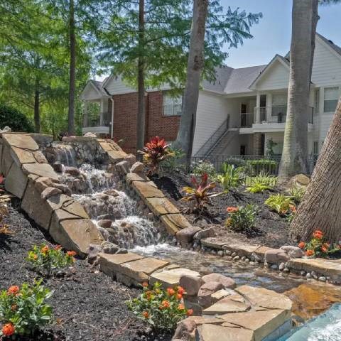 A small waterfall in a garden in front of a house.