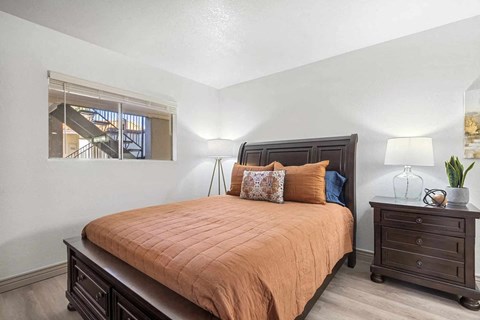 A bedroom with a bed, nightstand, and a window.