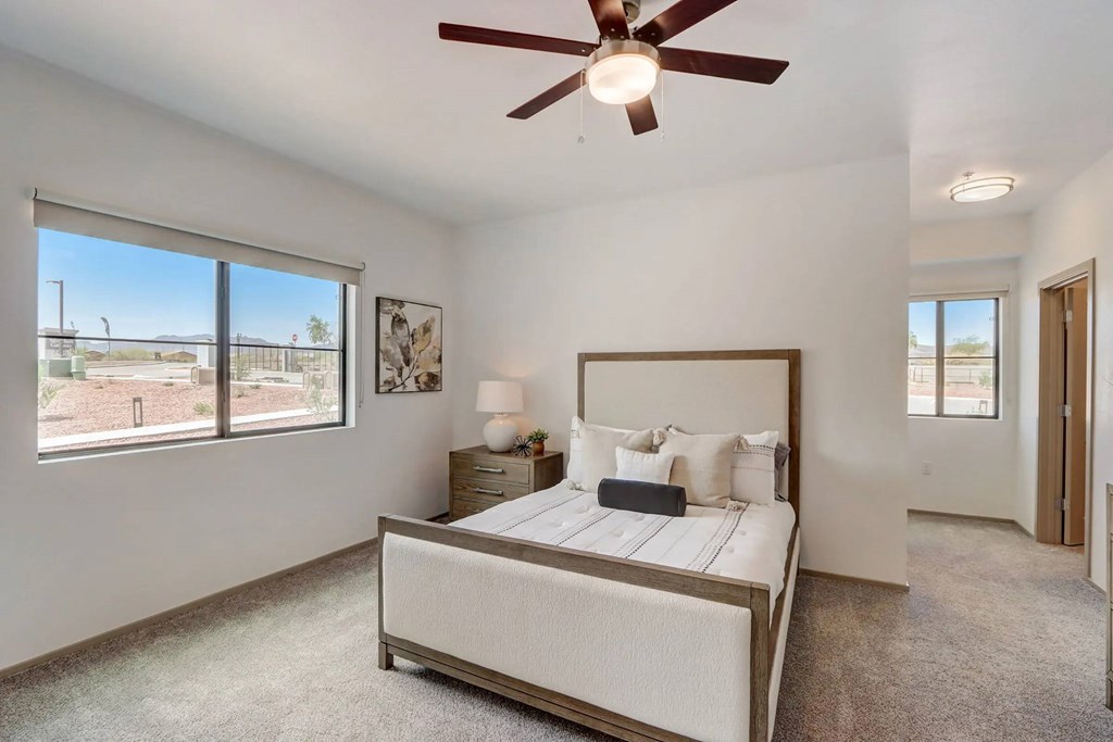A bedroom with a large bed and a ceiling fan.