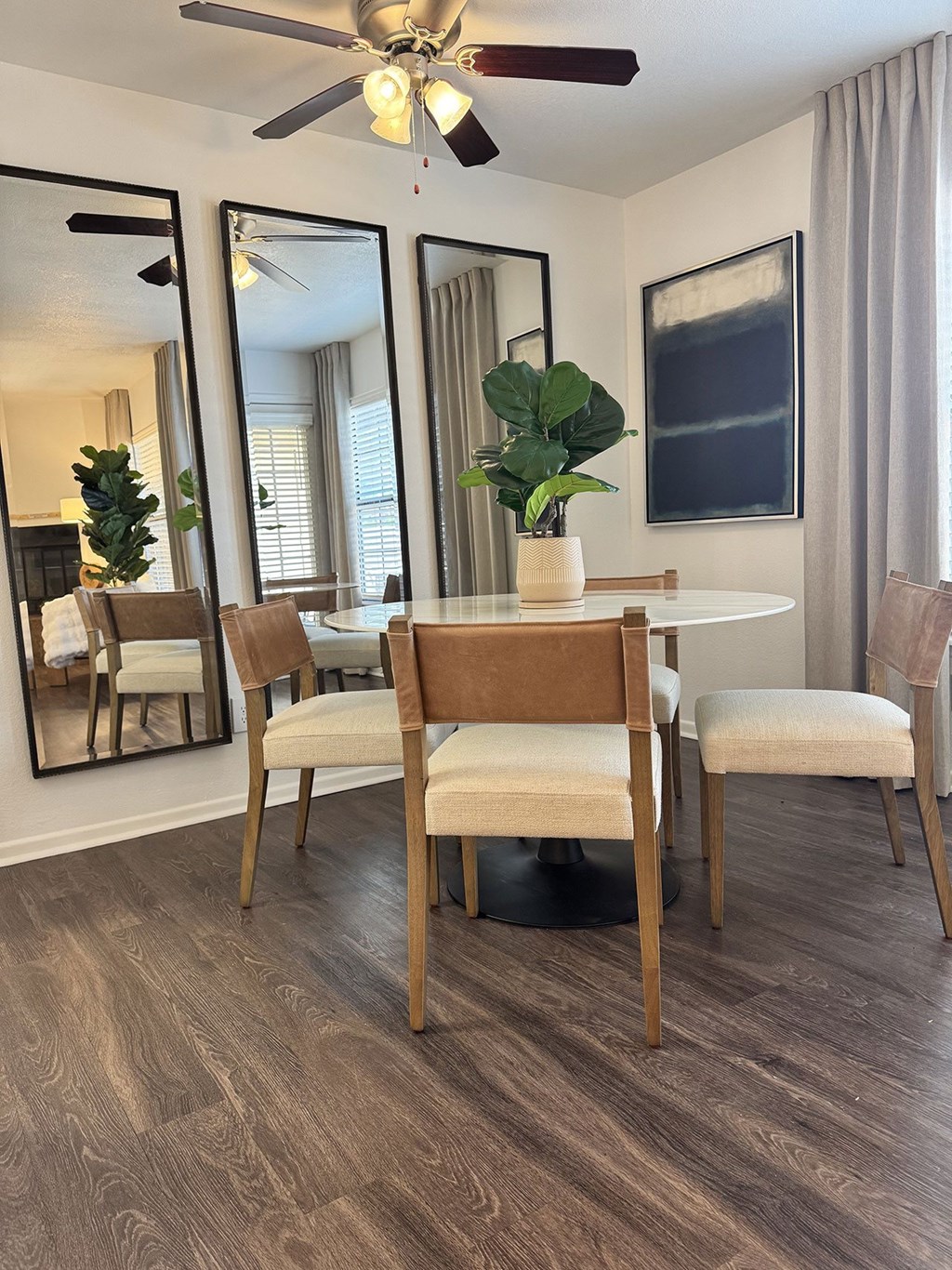 A dining room with a table, chairs, and a ceiling fan.