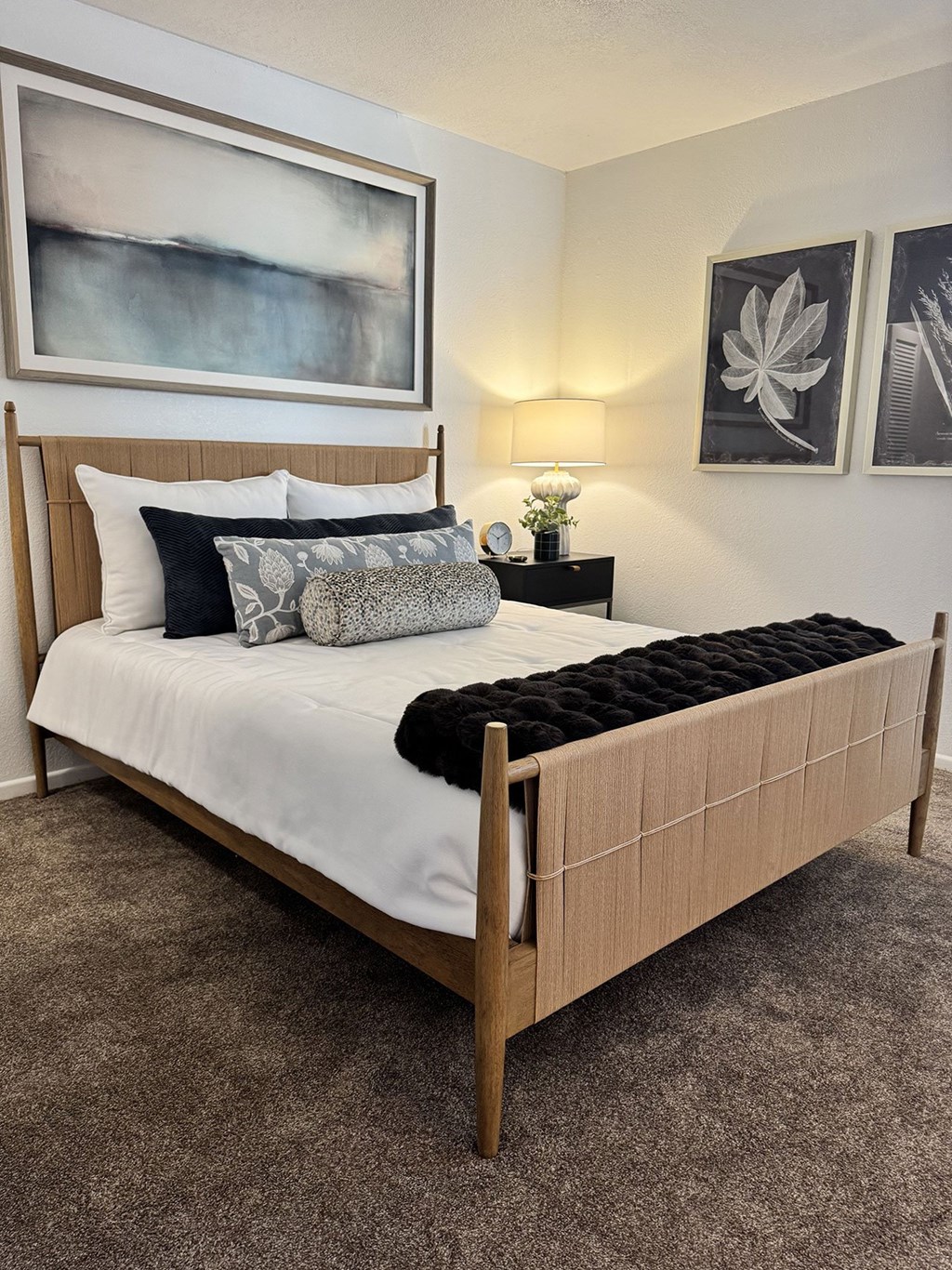 A bed with a wooden headboard and a black pillow on it.