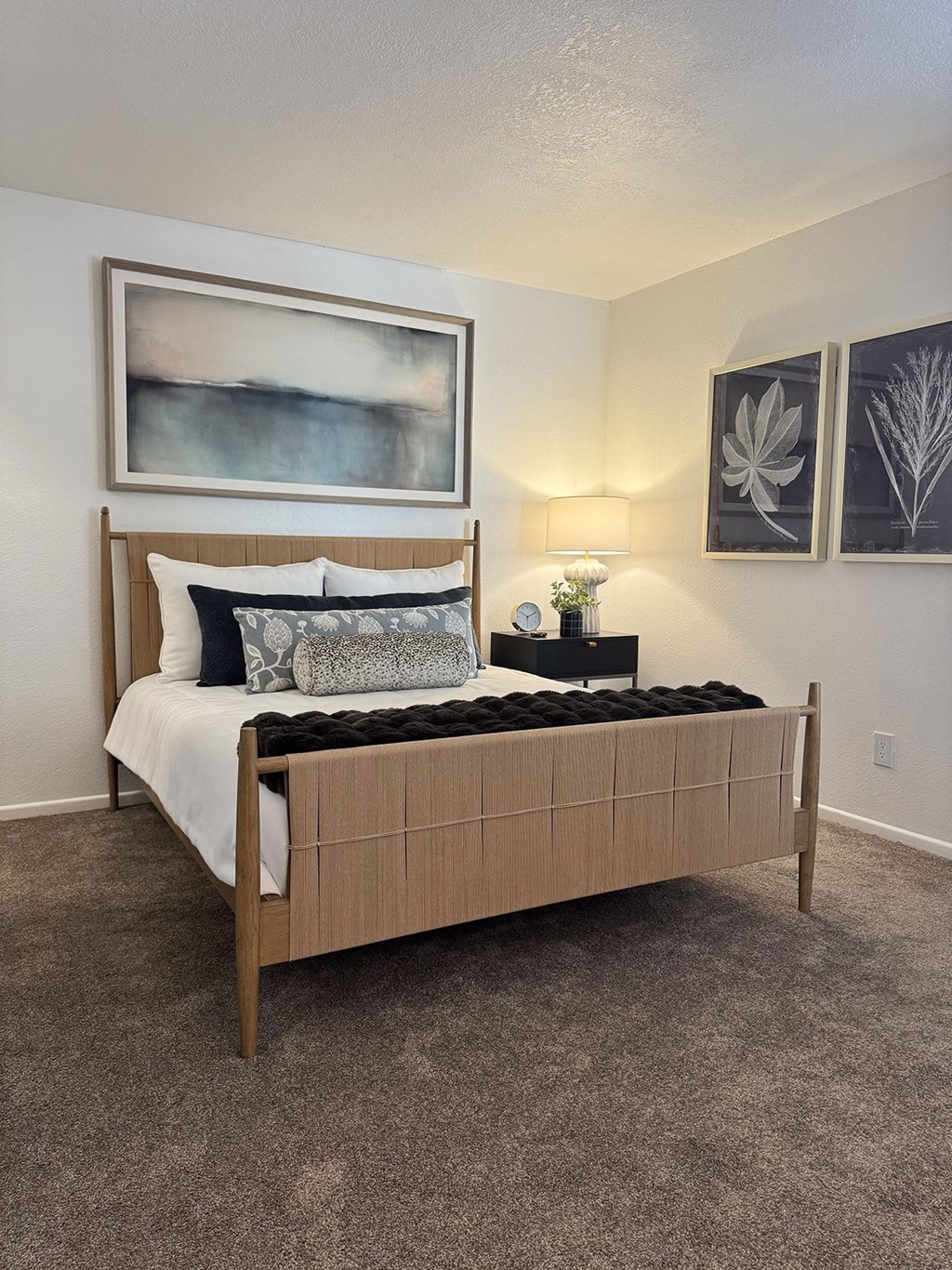 A bed with a wooden headboard and pillows is in a room with a painting on the wall.