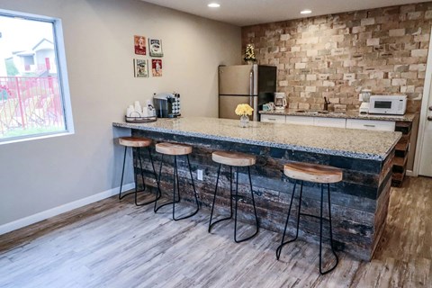 A kitchen with a bar area and four stools.