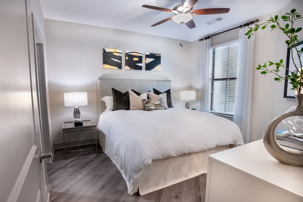 A bedroom with a bed, nightstand, and a ceiling fan.