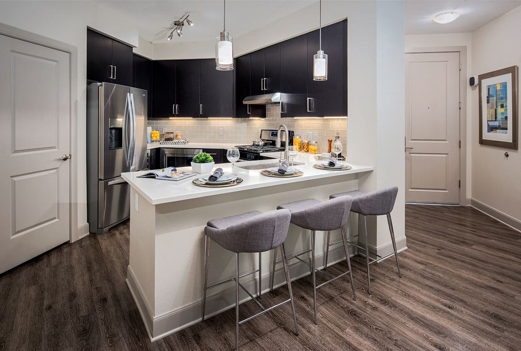 A kitchen with a white island and grey bar stools.
