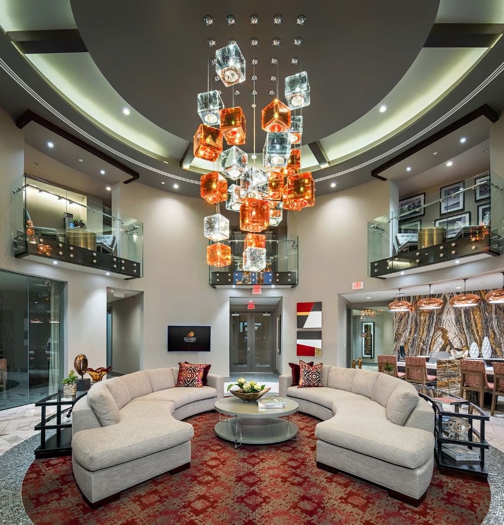 A modern living room with a large chandelier and a red carpet.