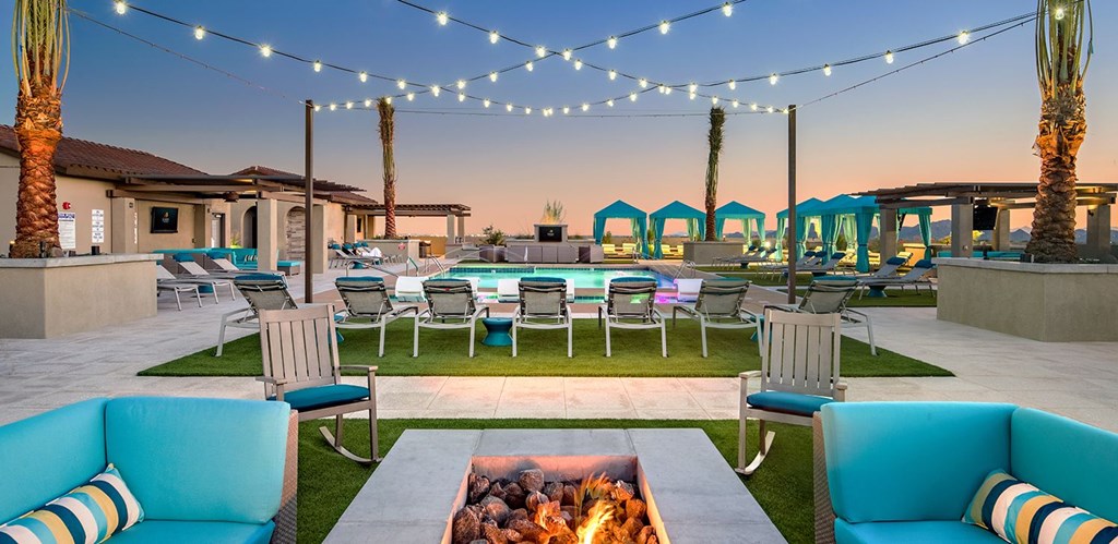 A patio with a fire pit and chairs.