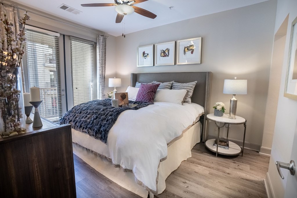 A bedroom with a bed, a side table, and a ceiling fan.