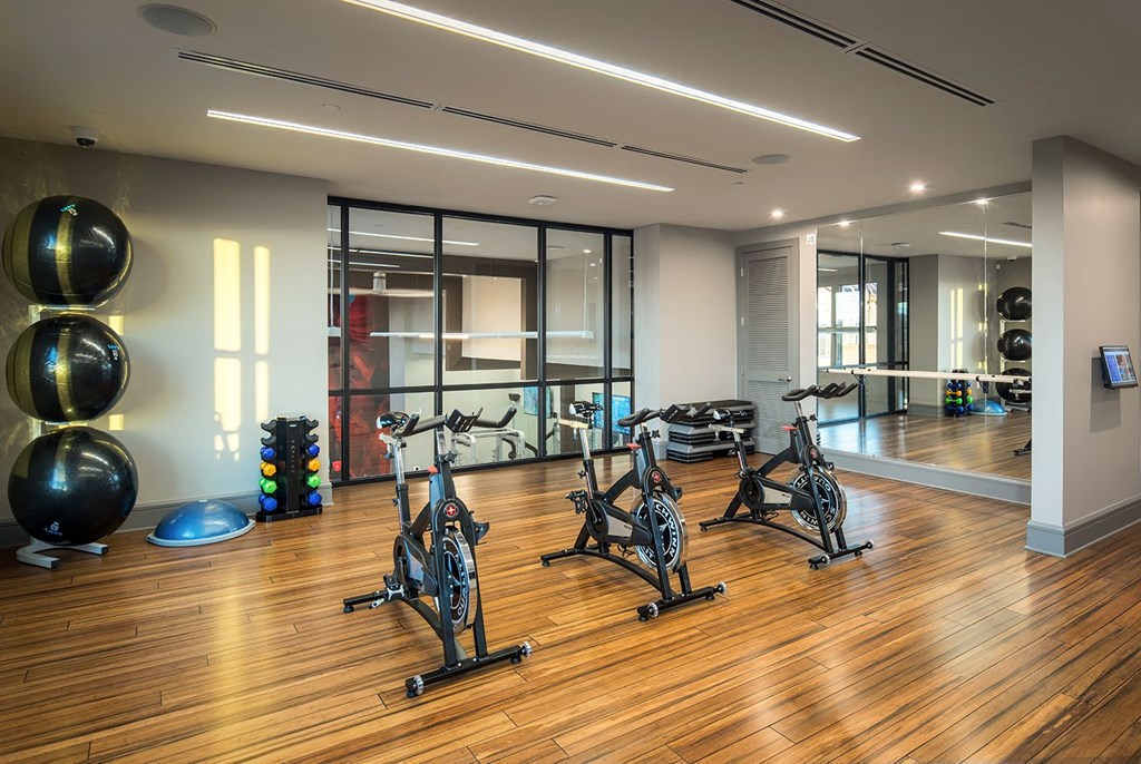A gym with wooden floors and exercise bikes.