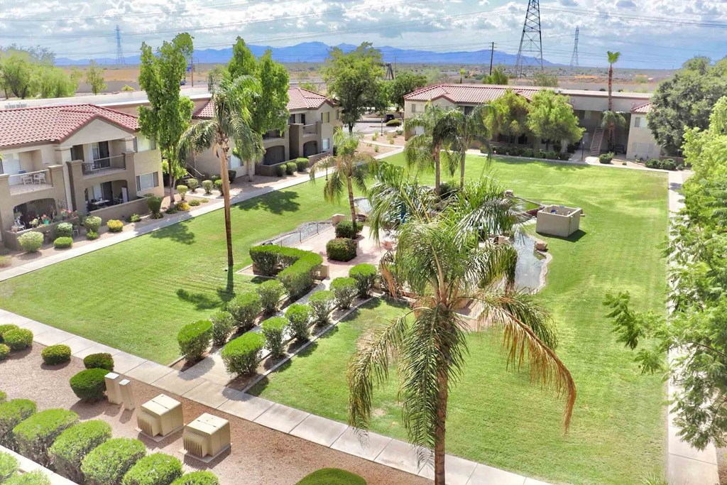 A view of a housing complex with a green lawn and palm trees.