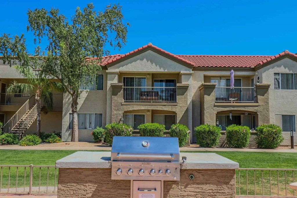 A grill is in front of a building with a red tile roof.