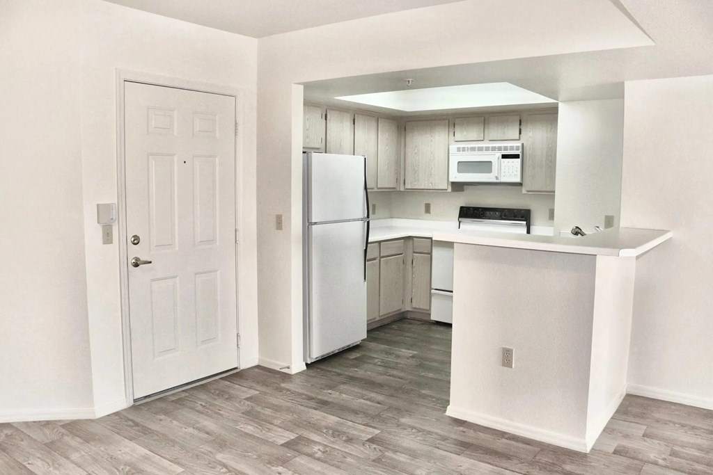 A kitchen with a refrigerator, microwave, and oven.