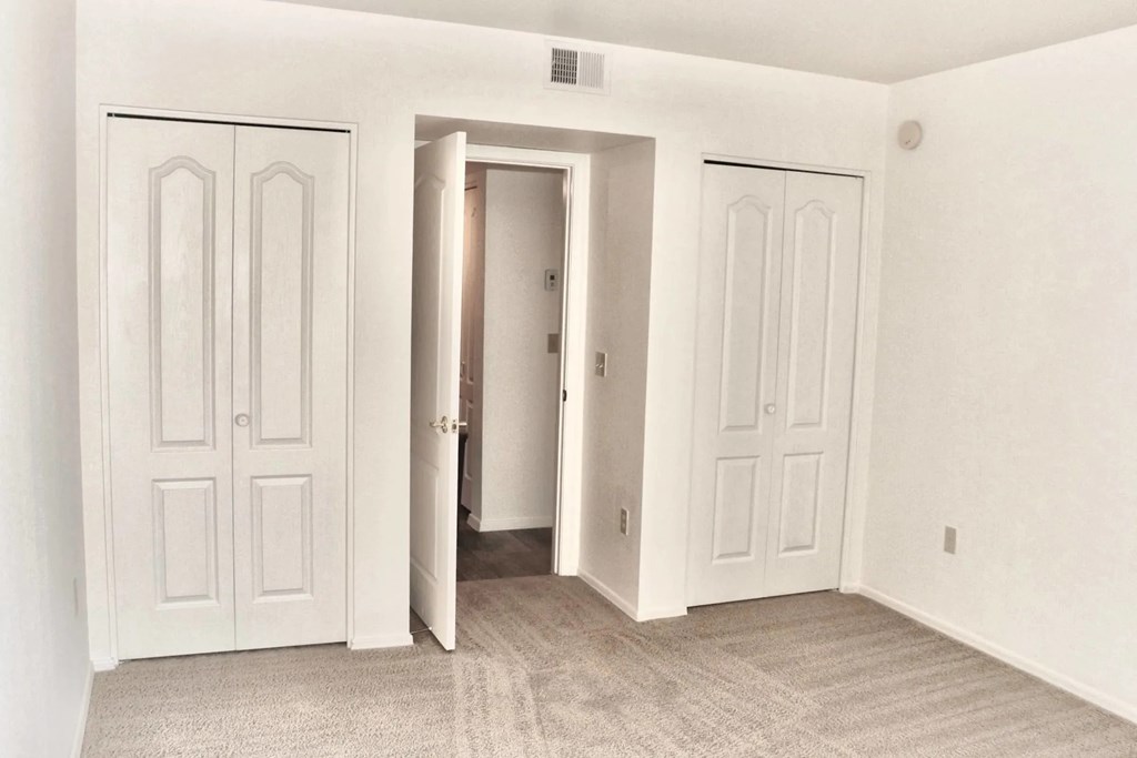 A white room with three doors and a carpeted floor.