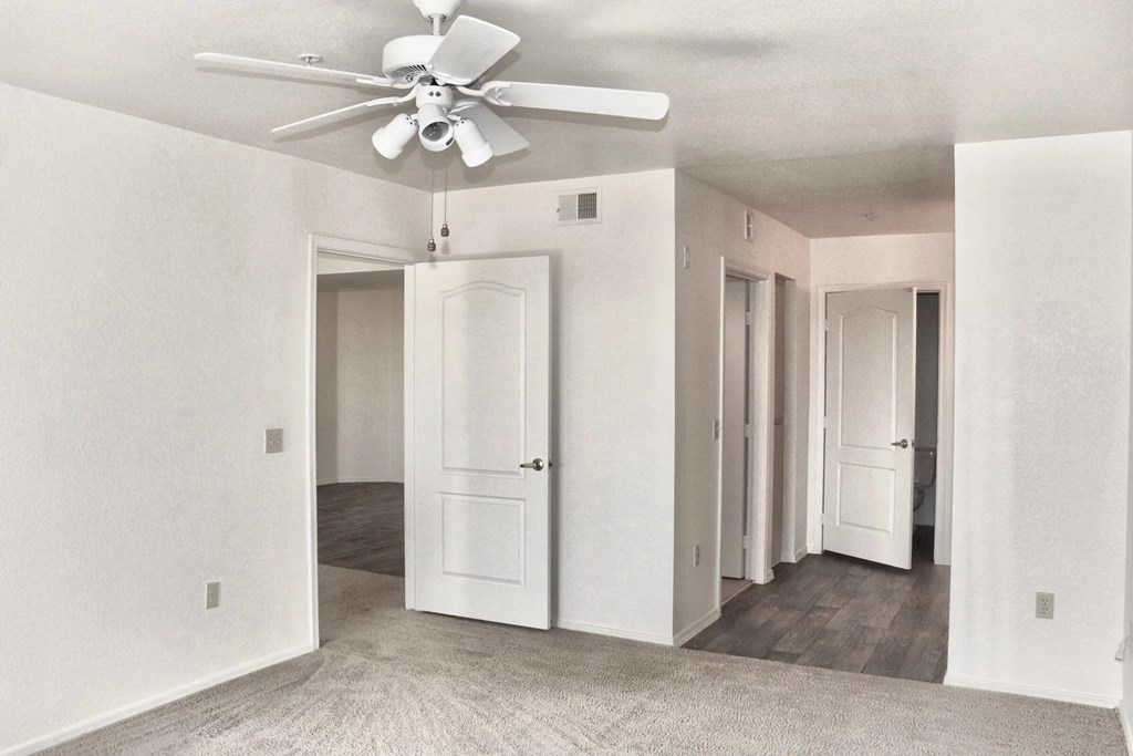 A white room with a ceiling fan and a carpeted floor.