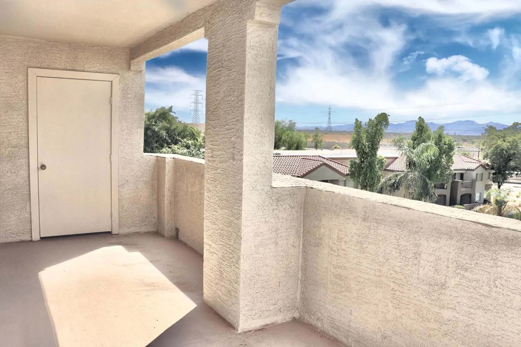 A balcony with a white door and a view of houses and trees.