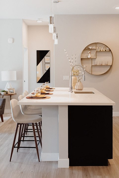 A modern kitchen with a white island and black bar stools.