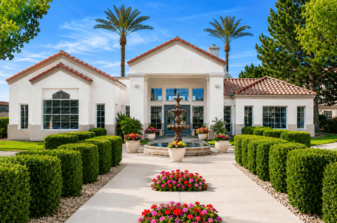 A white house with a red tile roof and a garden in front.