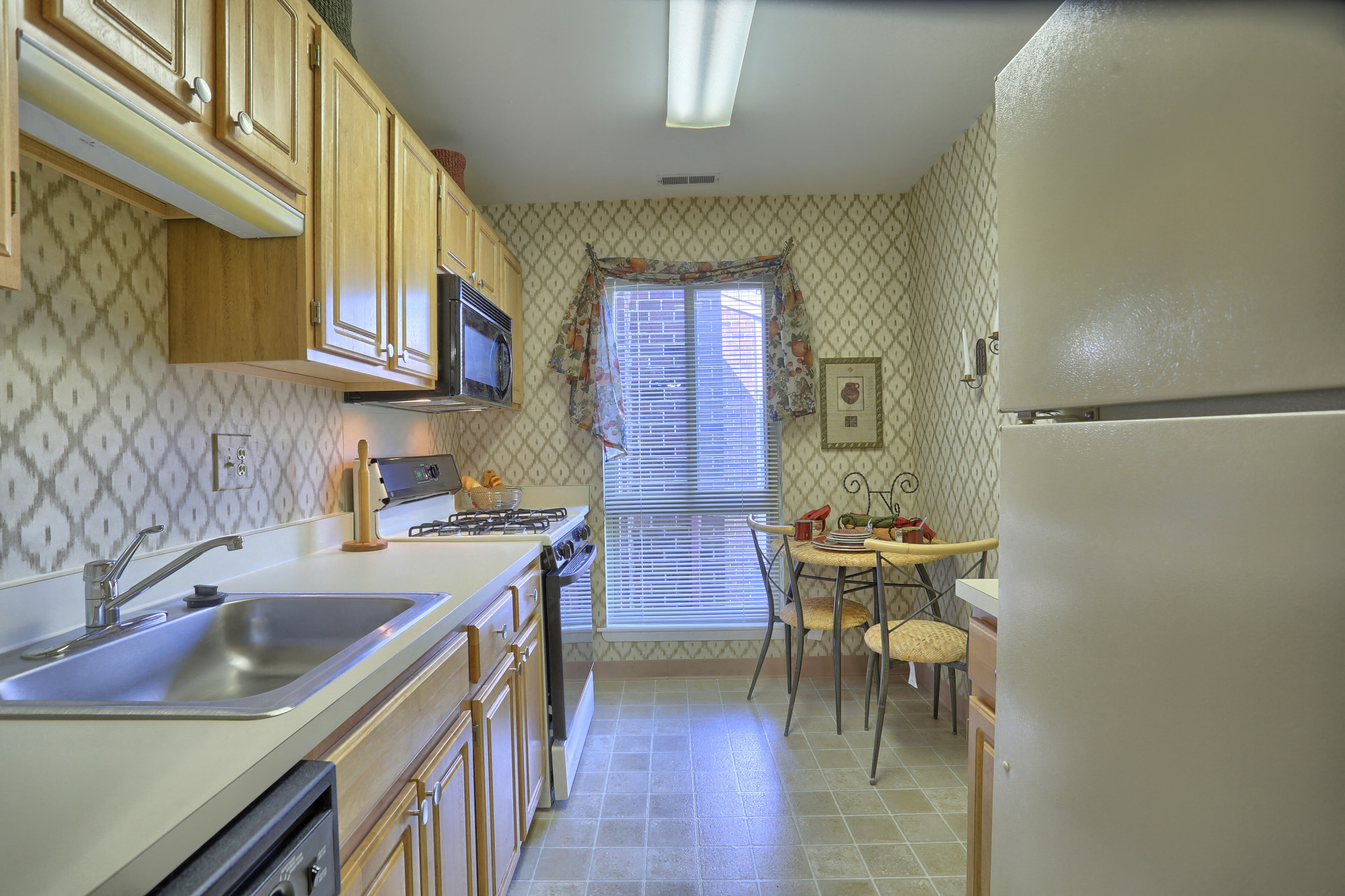 A kitchen with wooden cabinets and a tile floor.