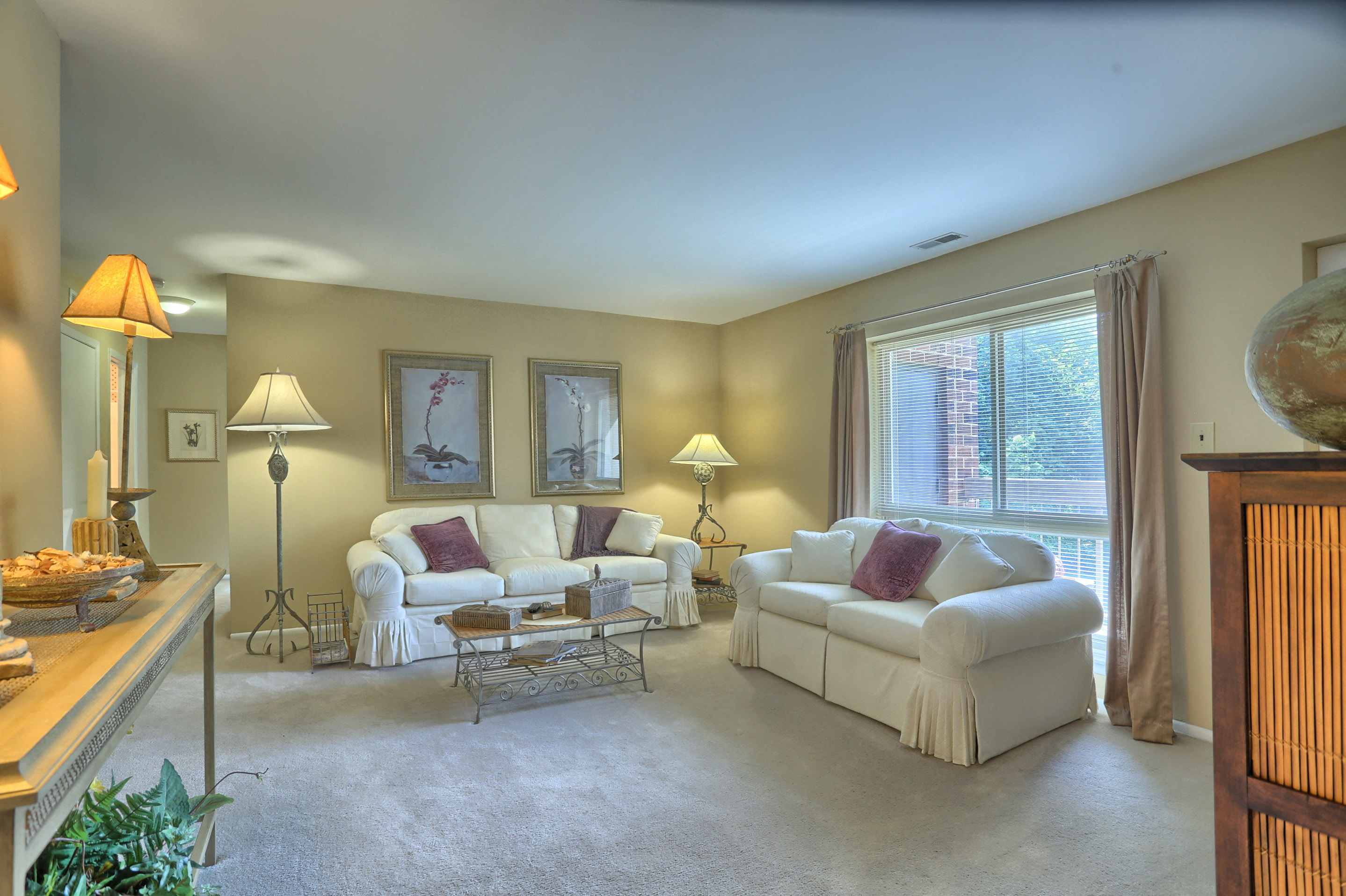 A living room with a white couch and a white chair.