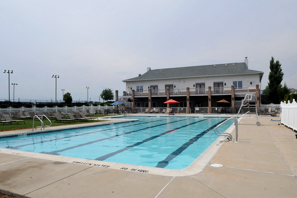A large swimming pool with lanes marked out and a building in the background.