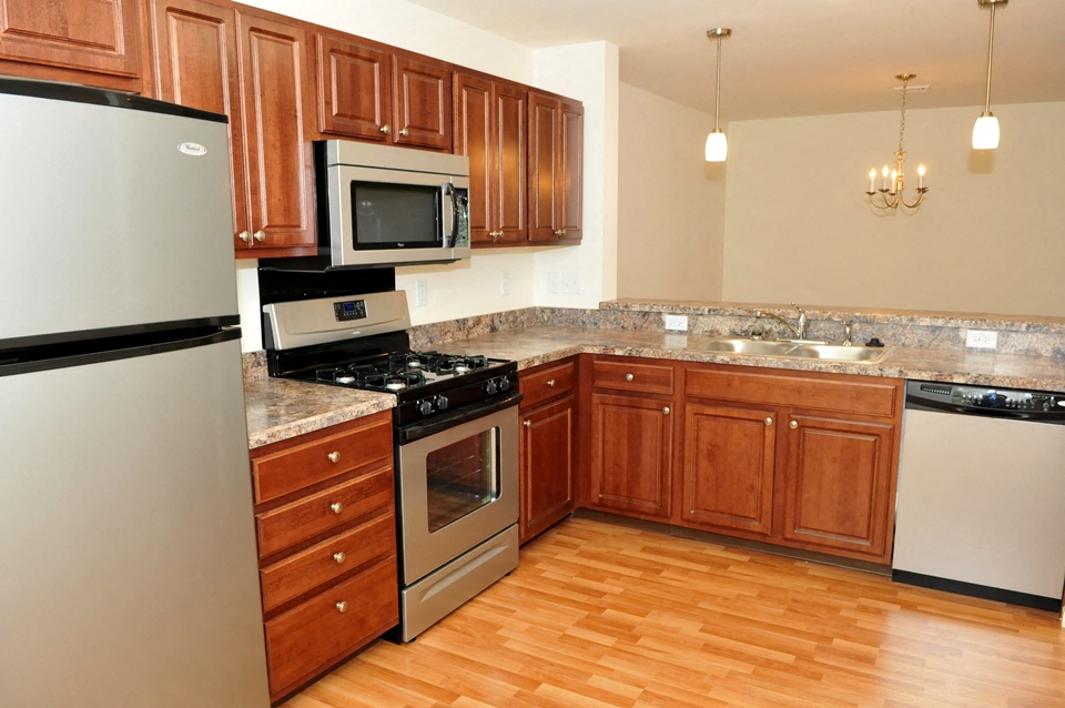 A kitchen with wooden cabinets and a stainless steel refrigerator.