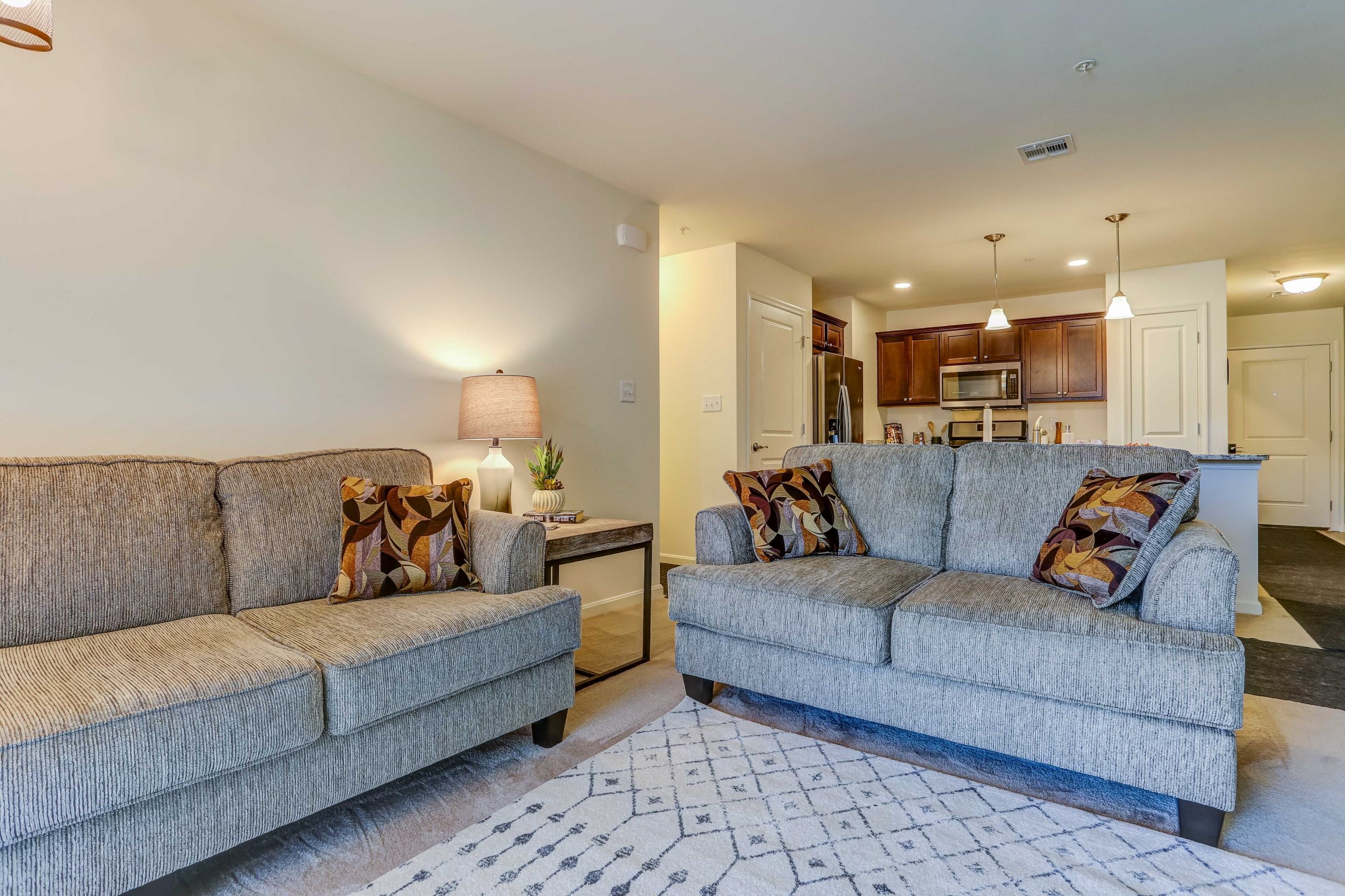 Two grey couches with pillows in a living room.
