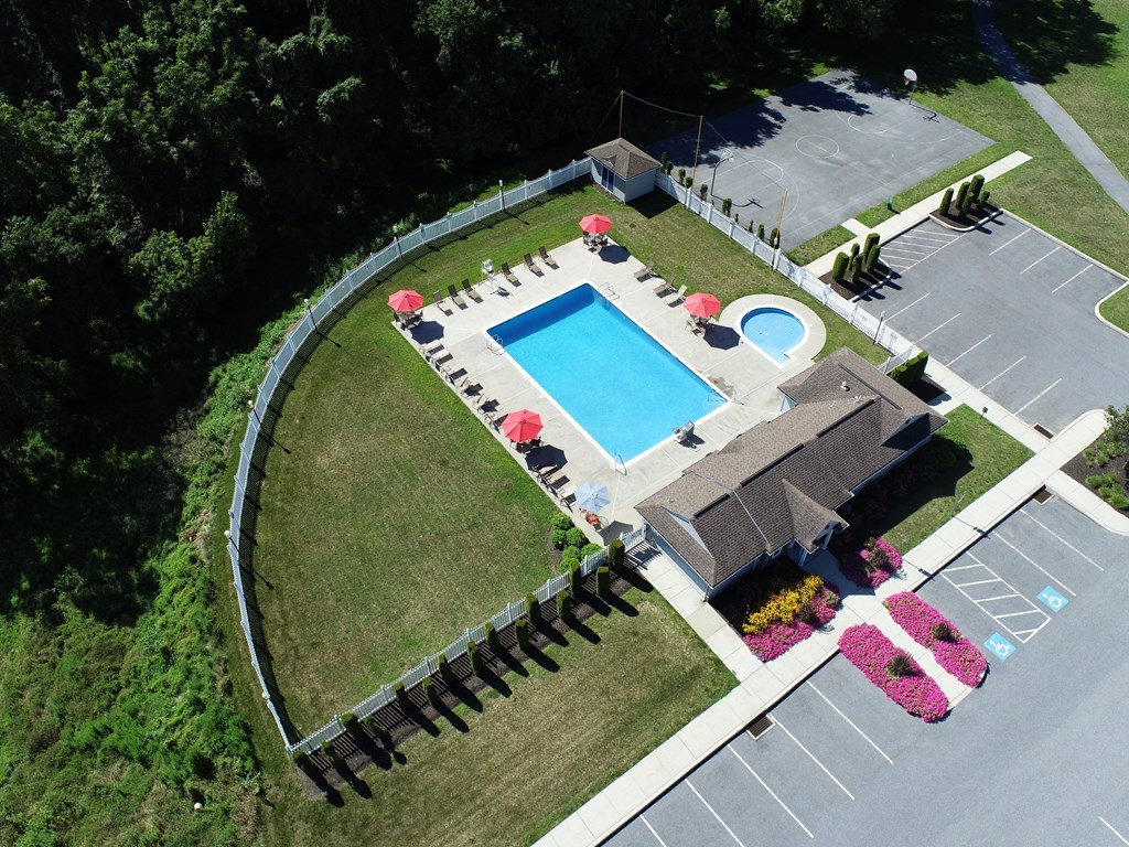 arial view of a swimming pool in a backyard with a lawn and a house