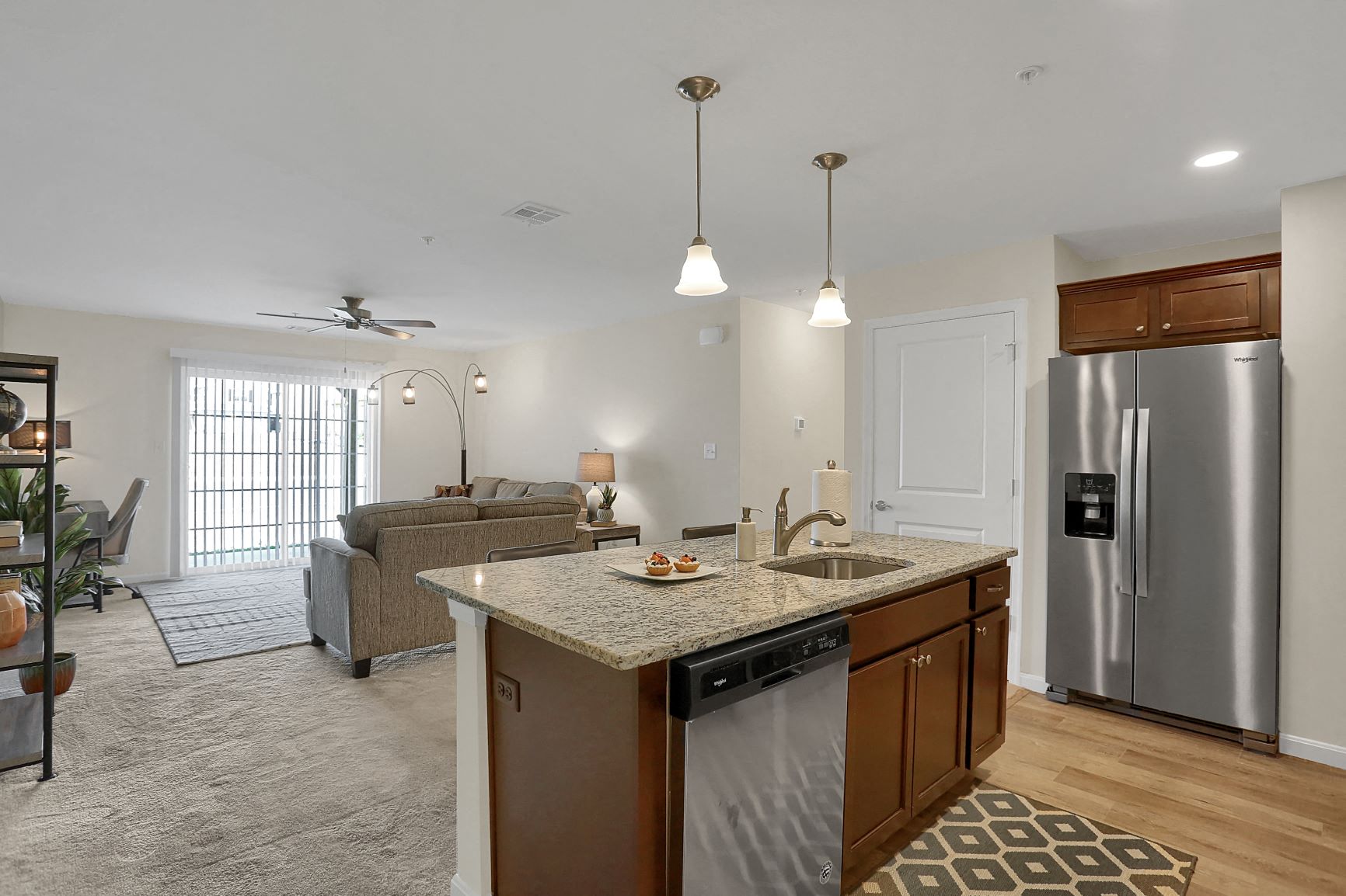A kitchen with a refrigerator, sink, and a dining table with chairs.